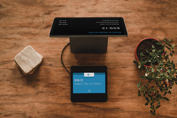 Counter POS tablet showing real-time billed order tally and payment terminal on wooden countertop